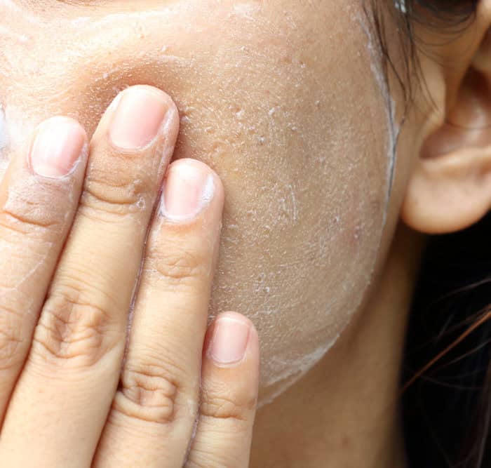 woman exfoliating face