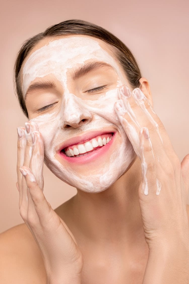 woman washing face with cleanser