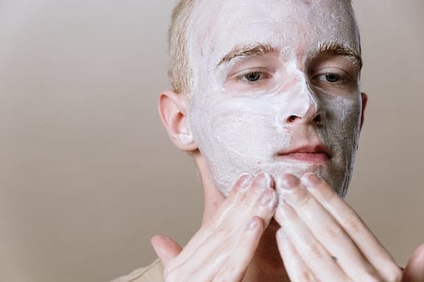 male washing face with cleanser